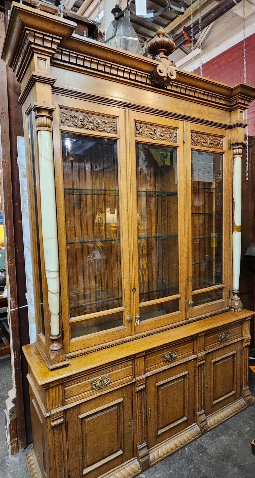 TALL 2 PIECE AMERICAN OAK DISPLAY CABINET WITH BEVELED GLASS DOORS, GLASS SHELVES AND ONYX COLUMNS