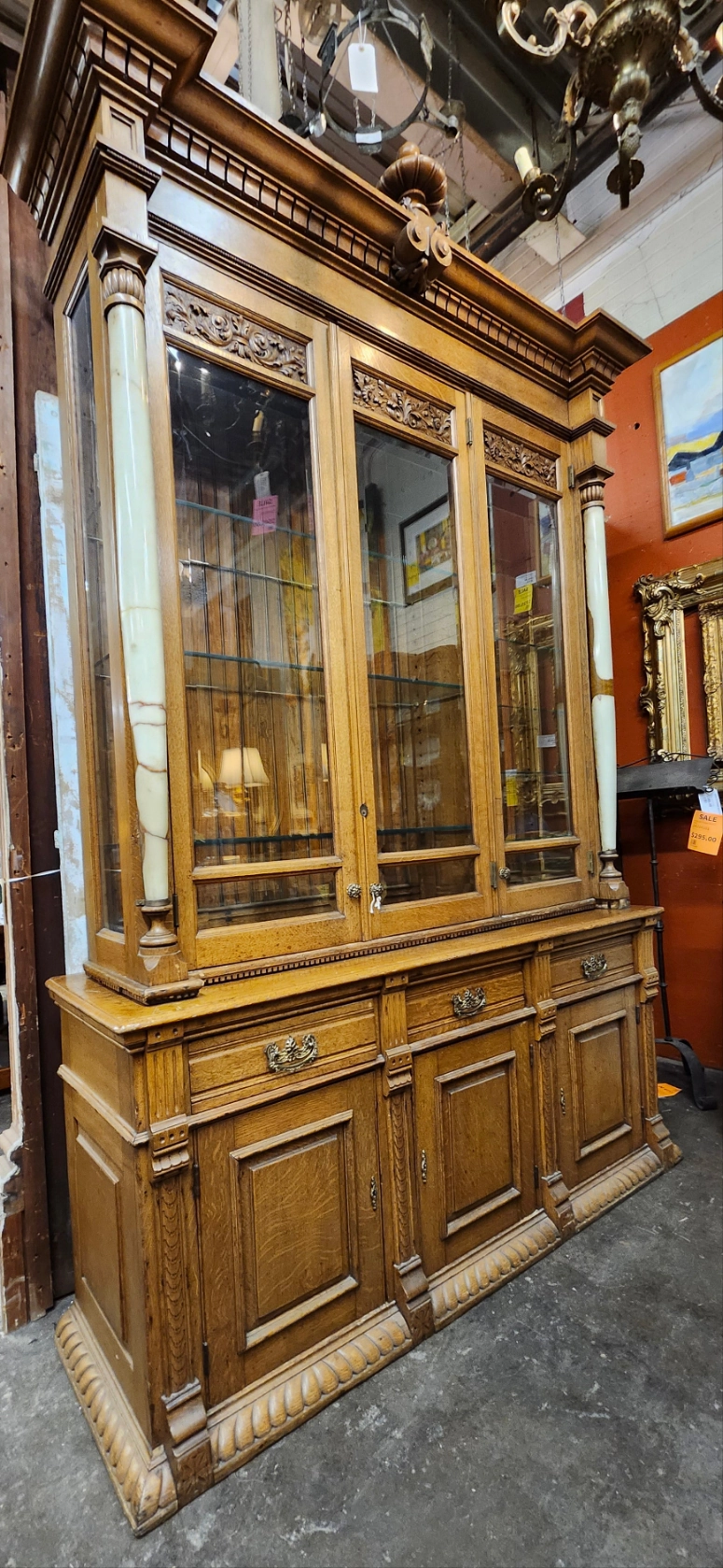 TALL 2 PIECE AMERICAN OAK DISPLAY CABINET WITH BEVELED GLASS DOORS, GLASS SHELVES AND ONYX COLUMNS